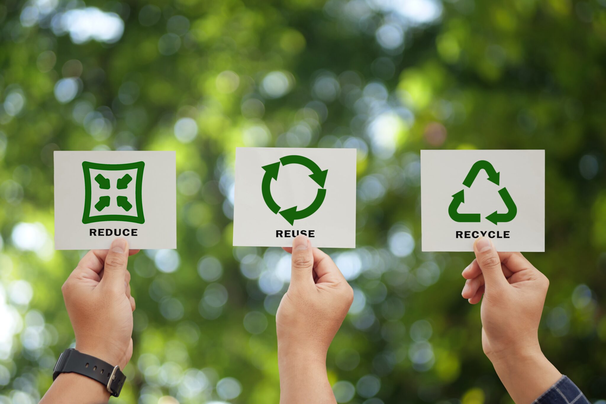 Hand,Holding,Reduce,,Reuse,,Recycle,Symbol,On,Green,Bokeh,Background.